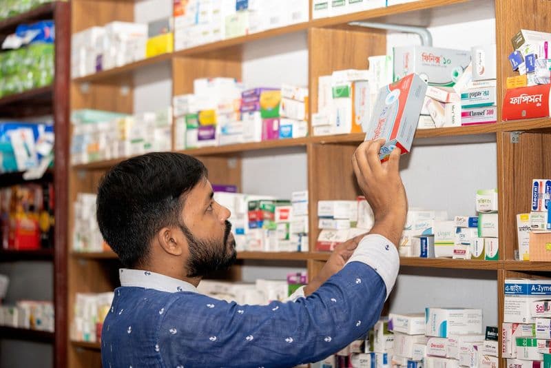 Un pharmacien range des médicaments sur les étagères