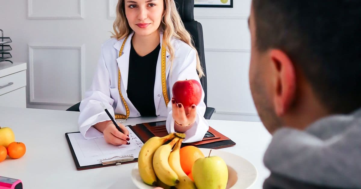 Une diététicienne reçoit un patient en consultation, une corbeille de fruits sur le bureau