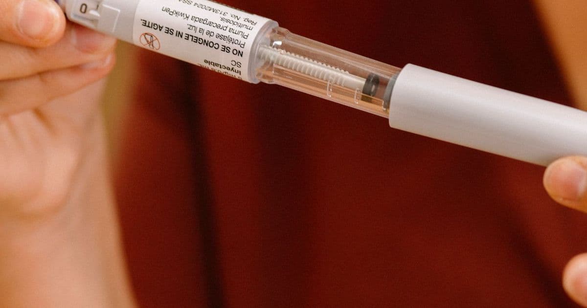Gros plan sur un stylo injecteur tenu entre deux mains