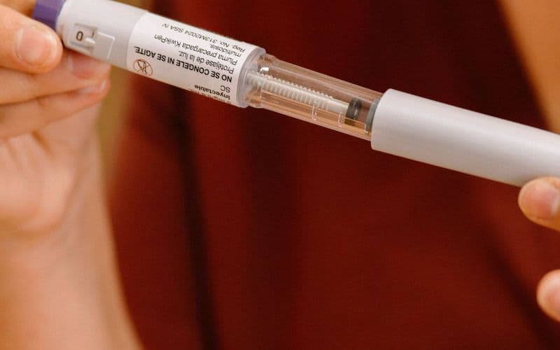 Gros plan sur un stylo injecteur tenu entre deux mains