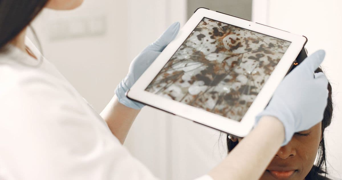 Une professionnelle de santé examine la peau d’une patiente avec un outil numérique