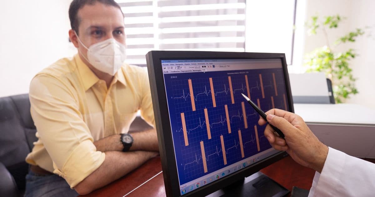 Un médecin commente un électrocardiogramme à l’écran face à son patient
