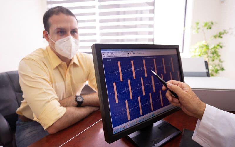Un médecin commente un électrocardiogramme à l’écran face à son patient