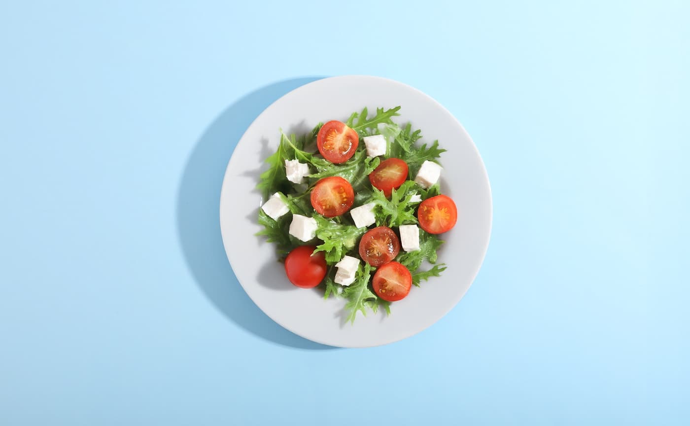 Salade de tomates fraîches et fromage photographiée en lumière naturelle