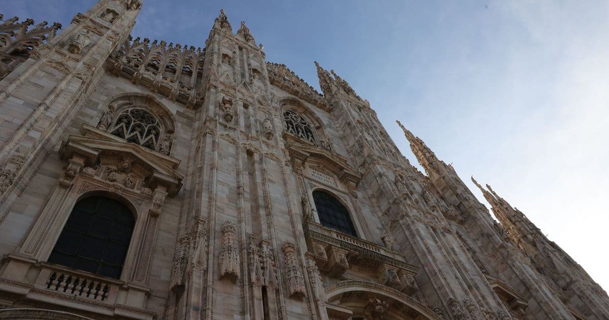 La façade gothique du Duomo de Milan vue en contre-plongée sous un ciel dégagé