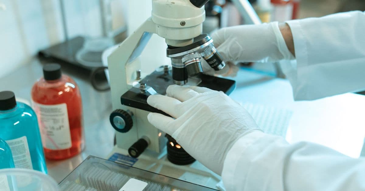 Une scientifique analyse un échantillon au microscope
